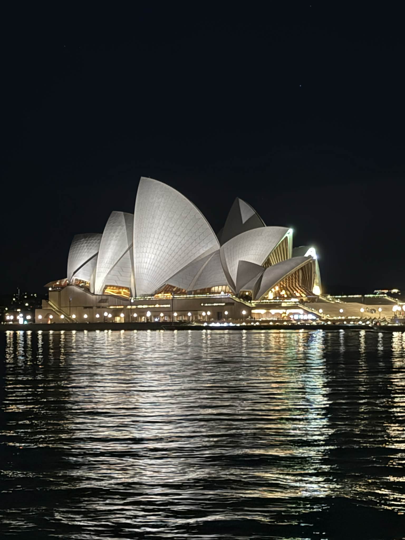 The supplied photo of the Sydney Opera House at night, with lights reflected in the water.